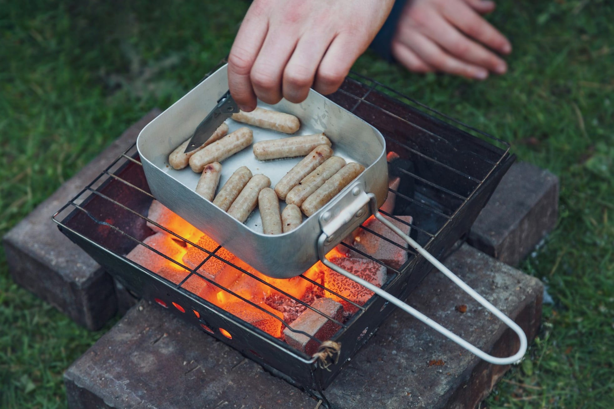 pan of uncooked sausages on grill